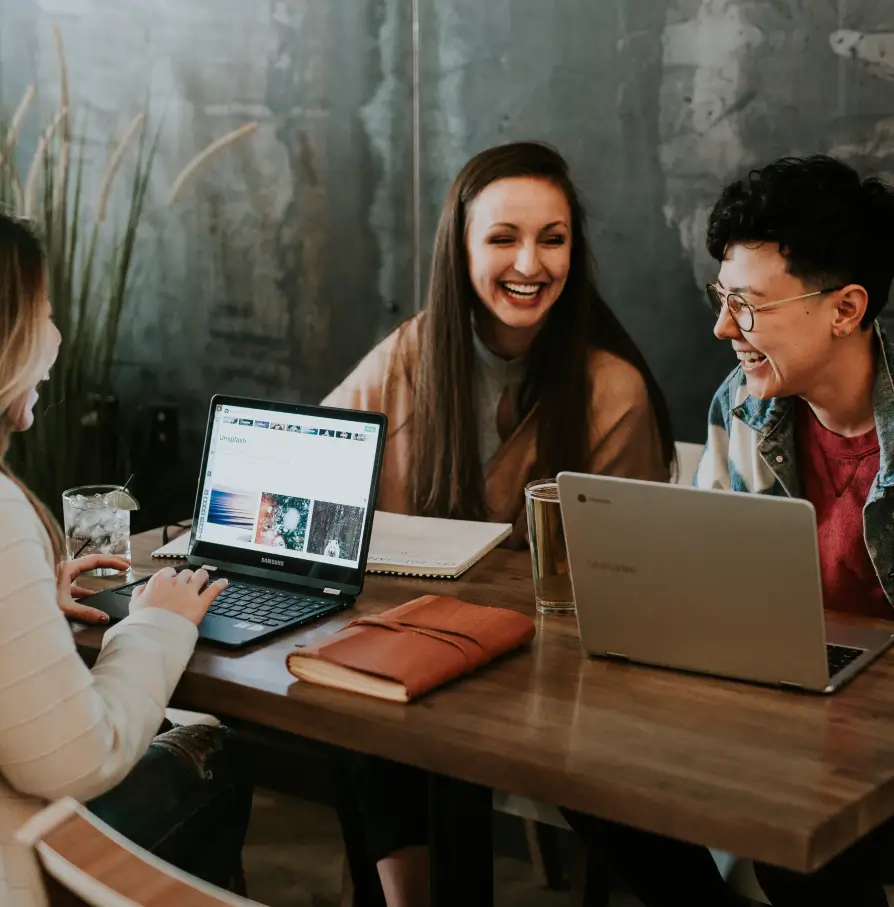 groupe de jeunes adultes travaillant ensemble sur des ordinateurs portables dans un café
