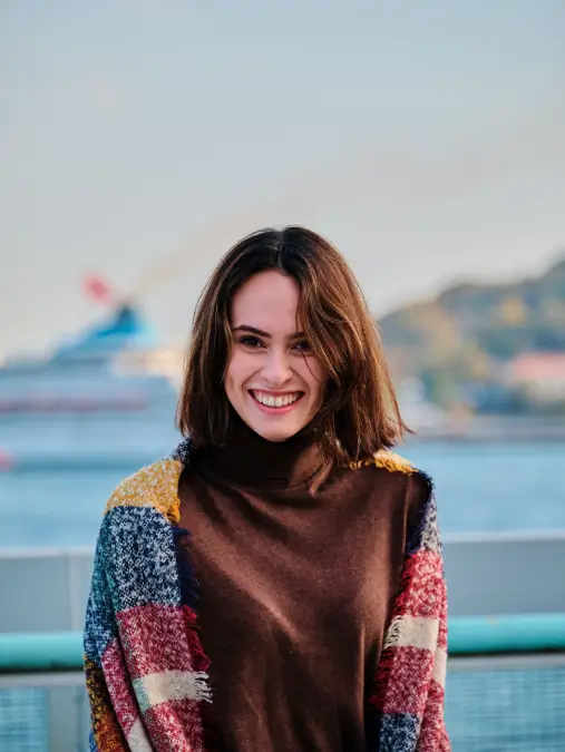 femme souriante avec écharpe colorée devant un bateau flou