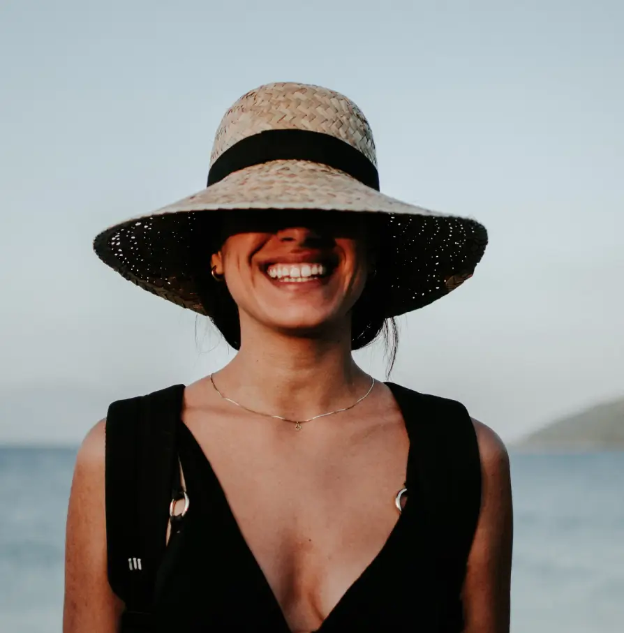 femme souriante portant un chapeau de paille sur la plage