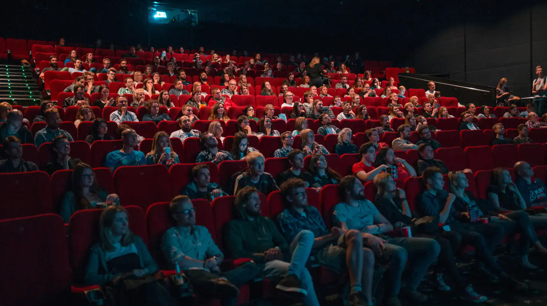 salle de cinéma remplie de spectateurs assis sur des sièges rouges